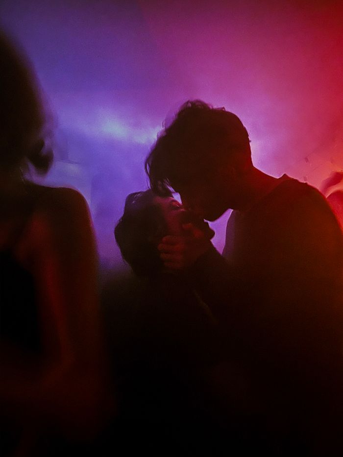 A couple embracing passionately under colorful nightclub lights, exuding romance.