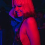 A woman enjoys vibrant nightlife in a nightclub, surrounded by colorful lights, embodying nightlife energy.